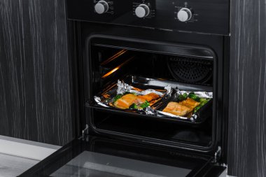 Mutfakta siyah konveksiyon fırını var. fırında somon.