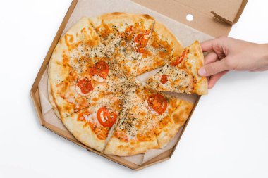 Erkek eli beyaz arka planda açık bir kutuda bir dilim margarita pizzası tutuyor. Yemek servisi. Karantina altındaki yiyecekler