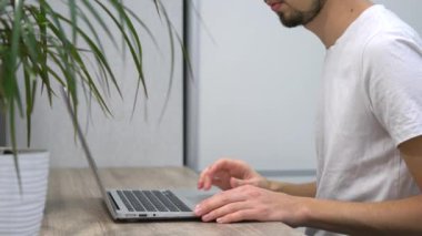 Evdeki bilgisayarda çalışan bir adam. 2020 karantinası sırasında evde çalışan bir kişi bilgisayarda yazar.