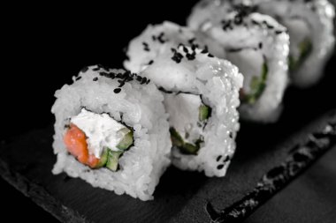 Siyah arka planda ton balığı ve krem peynirli rulo. Japon yemeklerini yakından çek. Makro fotoğraf. sebze yemeği.