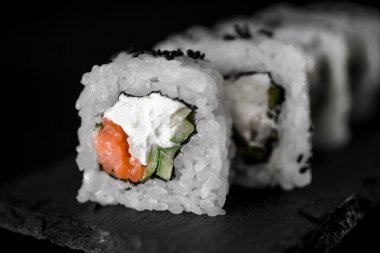 Siyah arka planda ton balığı ve krem peynirli rulo. Japon yemeklerini yakından çek. Makro fotoğraf. sebze yemeği.