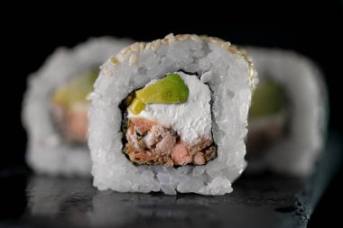 Siyah arka planda ton balığı ve krem peynirli rulo. Japon yemeklerini yakından çek. Makro fotoğraf. sebze yemeği.