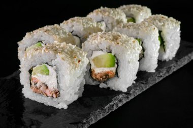 Siyah arka planda ton balığı ve krem peynirli rulo. Japon yemeklerini yakından çek. Makro fotoğraf. sebze yemeği.