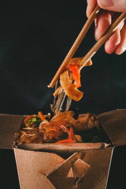 Deniz mahsullü funchoza. Adam sebzeli spagetti yiyor. Yemek servisi. Paket yemek. Çin yemeği. Japon eriştesi.