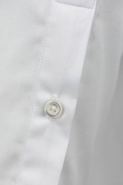 Klasik beyaz gömlekte beyaz inci düğme. makro fotoğraf. Bir iş adamı için kıyafet. Pamuk adamın gömleğini yakından çek.