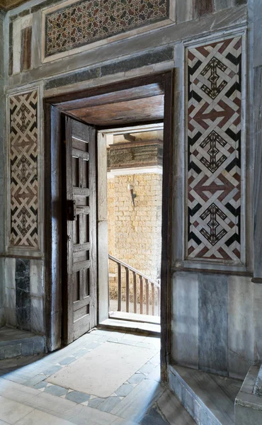 Vista en ángulo de una puerta abierta ornamentada envejecida de madera que conduce a un pasaje iluminado brillante — Foto de Stock