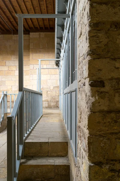 Stone staircase leading to a narrow passage framed by blue wooden doors and balustrade