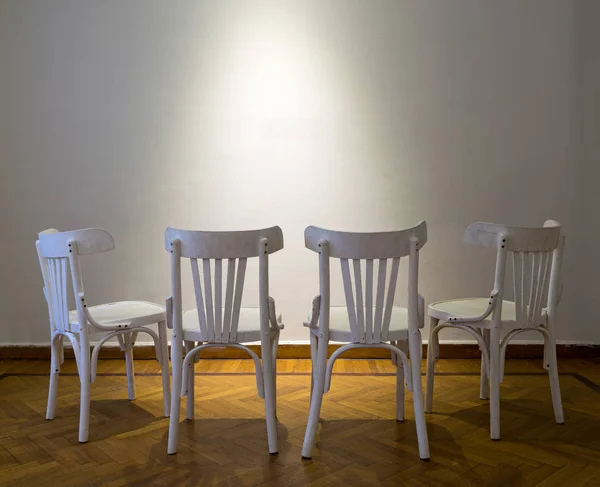 Cuatro sillas de madera blanca frente a la pared blanca en suelo de parquet de madera — Foto de Stock