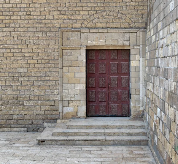 Деревянная украшенная красная дверь на кирпичных каменных стенах и лестницах — стоковое фото