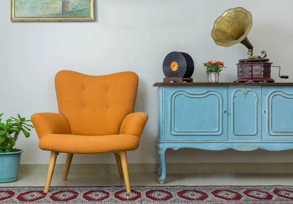 Sillón retro naranja, aparador vintage azul claro de madera, fonógrafo antiguo (gramófono), discos de vinilo sobre fondo de pared beige, suelo de porcelana alicatada y alfombra roja — Foto de Stock