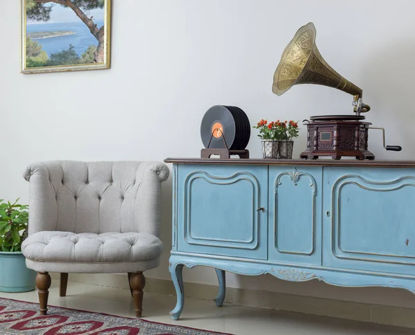 Sillón blanco retro, aparador azul claro de madera vintage, fonógrafo antiguo (gramófono) y discos de vinilo sobre fondo de pared beige, suelo de porcelana alicatada y alfombra roja — Foto de Stock