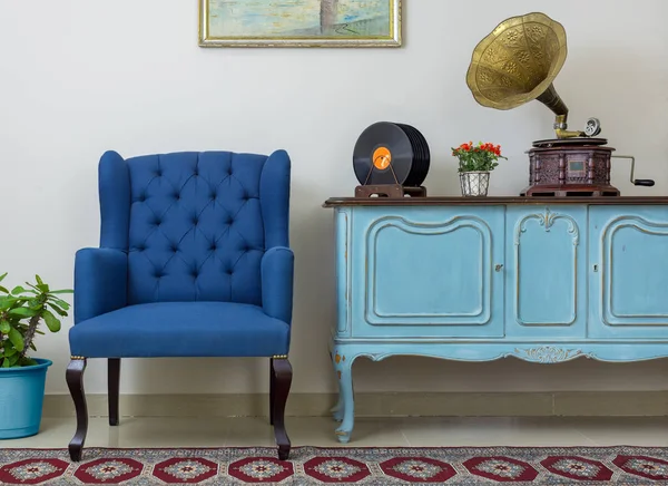 Sillón azul retro, aparador azul claro de madera vintage, fonógrafo antiguo (gramófono), discos de vinilo sobre fondo de pared beige, suelo de porcelana alicatada y alfombra roja — Foto de Stock