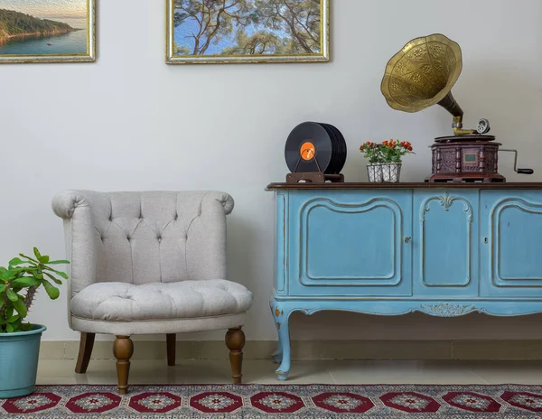 Sillón blanco retro, aparador azul claro de madera vintage, fonógrafo antiguo (gramófono) y discos de vinilo sobre fondo de pared beige, suelo de porcelana alicatada y alfombra roja — Foto de Stock