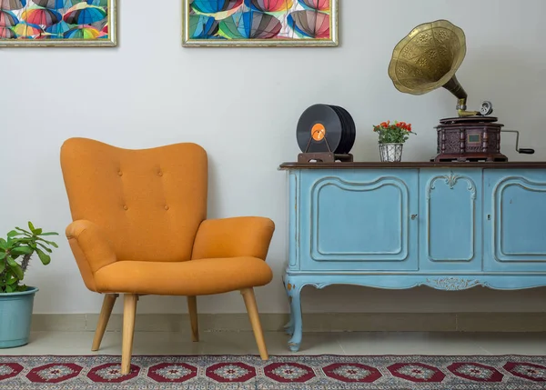 Sillón retro naranja, aparador vintage azul claro de madera, fonógrafo antiguo (gramófono), discos de vinilo sobre fondo de pared beige, suelo de porcelana alicatada y alfombra roja — Foto de Stock