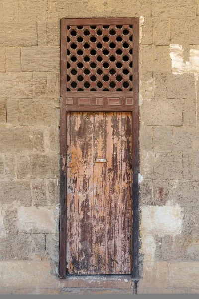 Старая заброшенная каменная кирпичная стена с выветренной деревянной дверью и окнами, покрытые деревянной решеткой, Старый Каир, Египет — стоковое фото