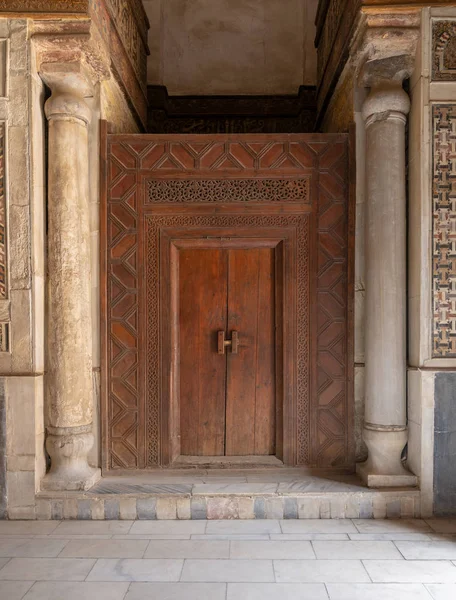 Puerta de madera vieja enmarcada por paneles grabados de madera decorados con patrones geométricos y florales y dos columnas talladas, El Cairo, Egipto — Foto de Stock