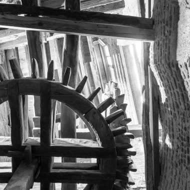 Eski su değirmeninin altından çıkan siyah-beyaz yıpranmış değirmen binasının içine dönüyor.