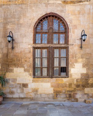 Terk edilmiş taş tuğlalar dövülmüş demir parmaklıklar pencere ve iki fener.