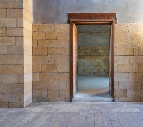 Puerta de madera abierta en ladrillos pared de piedra revelando habitación vacante con pared de ladrillos —  Fotos de Stock
