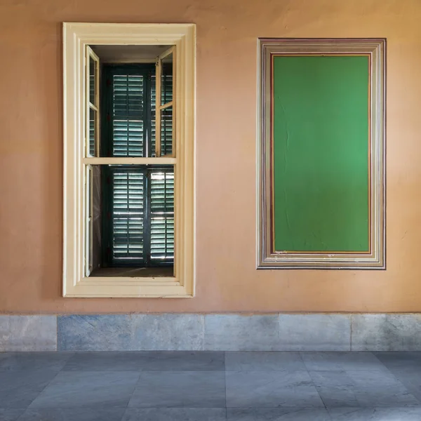 Marco verde con borde adornado y ventana con obturador verde cerrado en la pared naranja con suelo de mármol —  Fotos de Stock