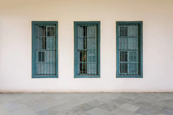 Weiße Wand mit drei grünen Grunge-Holzfensterläden, schmiedeeisernen Gittern und Marmorboden — Stockfoto