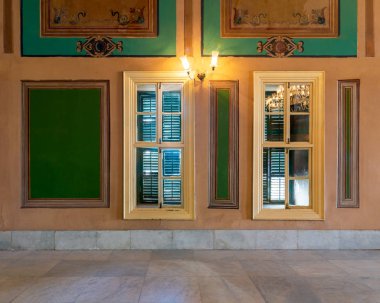 Yeşil panjurlu ahşap pencere. Turuncu duvarda zarif dikdörtgen yeşil çerçeveler.