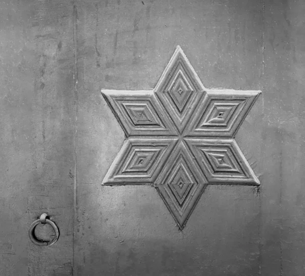 Decorations based on octagon star of David engraved on wooden door with door ring