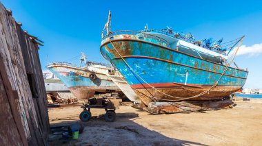 Old rusty ship under repairing on grungy dry dock in shipyard in old shipbuilding plant