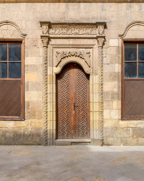 Fachada de pedra abandonada velha parede de tijolos decorados com porta de madeira arqueada e duas janelas — Fotografia de Stock