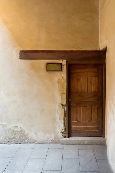 Puerta envejecida de madera en pared de piedra grunge y letrero de puerta de cobre envejecido en blanco —  Fotos de Stock