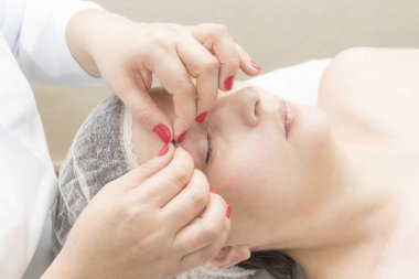 Masaj salonundaki genç bir kadına yüz masajı..