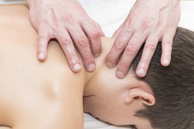 Genç bir çocuğa sırtından ve boynundan tıbbi masaj yapılıyor.
