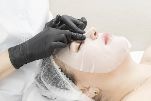 The procedure is a cleansing restorative wet mask for a woman in a beauty salon.