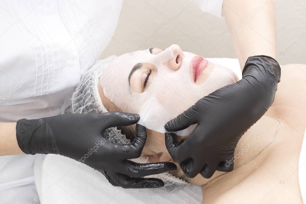 The procedure is a cleansing restorative wet mask for a woman in a beauty salon.