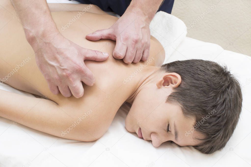 A teenage boy is given a medical massage of the back and neck