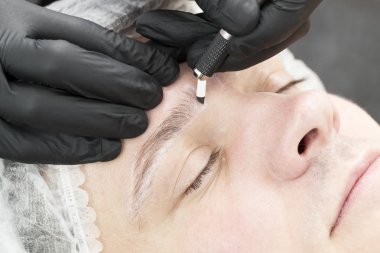 Erkekler için bir güzellik salonunda mikropatenli kaş dövme prosedürü.