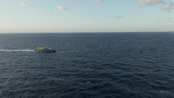 Aérea permaneciendo absolutamente quieta mientras un barco azul y amarillo cruza el horizonte — Vídeos de Stock