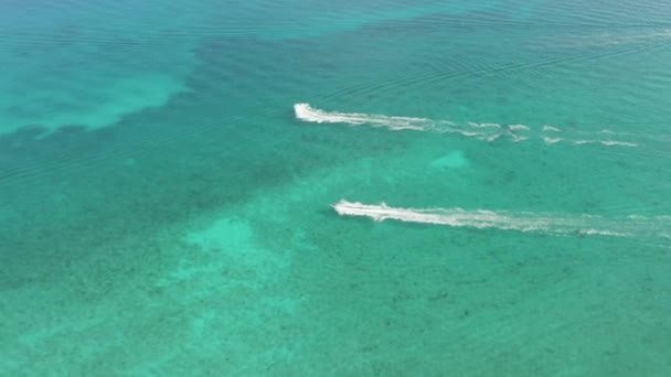 4k Вид с воздуха Отслеживание двух водных лыж, гоняющихся по аква-голубой Карибской воде — стоковое видео