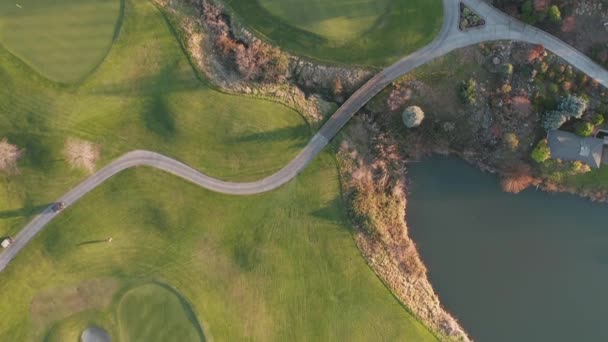 4k tiro aéreo sobre un campo de golf con hierba verde y personas moviéndose — Vídeos de Stock