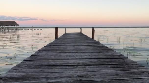 Fortfarande vy över Dock i Lake Bacalar wih Fantastisk rosa och gul solnedgång — Stockvideo
