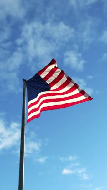 Κάθετη βολή της αμερικανικής σημαίας κυματίζει στον άνεμο και μπλε ουρανό ως φόντο — Αρχείο Βίντεο