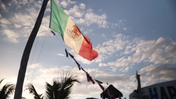 Zicht op Mexicaanse vlag waait in de wind tijdens het verplaatsen naar beneden met een mooie blauwe lucht — Stockvideo