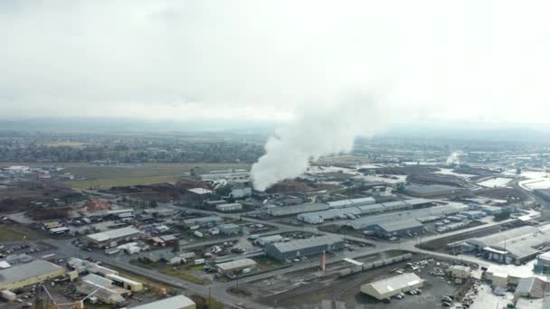 4k vedere aeriană care zboară spre o stivă industrială de fum în timp ce mașinile conduc de — Videoclip de stoc