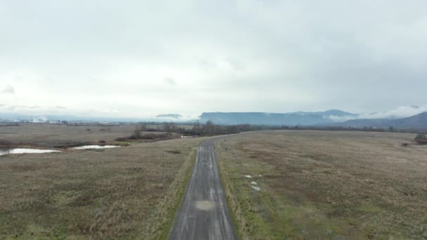 4k Вид с высоты птичьего полета по грязной дороге со скалой на заднем плане — стоковое видео