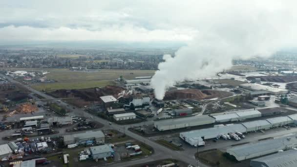 Vista aerea 4k che gira intorno a Smoke Stack sotto la pioggia in una zona industriale — Video Stock