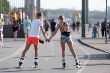 Moskova, Rusya, 26 Ağustos 2018. Kısa şortlu bir adam ve kız, Gorky Park 'taki Kırım seti üzerinde el ele tutuşuyorlar.