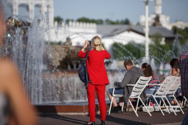 Kırmızı elbiseli kadın güneşli bir günde fıskiyenin fotoğrafını çekiyor.