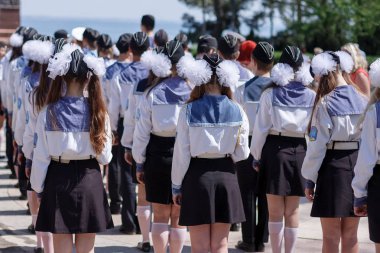 Odessa, Ukrayna, 6 Mayıs 2013. Saçları beyaz kurdeleli kızlar ve denizci üniformalı genç erkekler Karadeniz 'e tepeden bakan bilinmeyen bir denizcinin anıtının önünde dikiliyorlar.