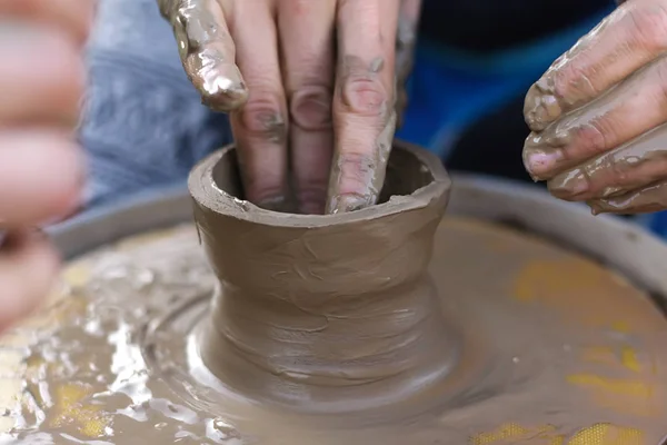 clay modeling, women\'s wet and dirty hands make a hole in the pot of clay on the Potter\'s wheel manual control on the master class on modeling