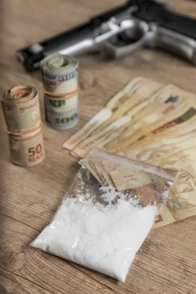 Geld, drugsand een kanon op een houten tafel — Stockfoto